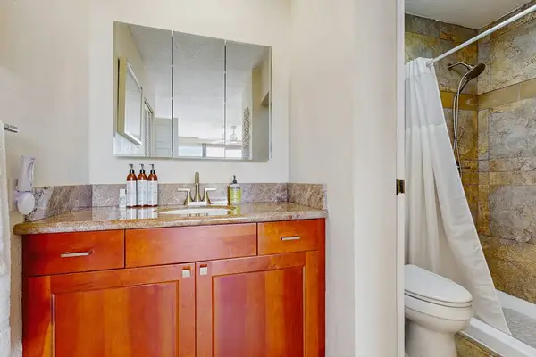 ​A clean, modern bathroom featuring a spacious wooden vanity and a convenient tub-shower combo