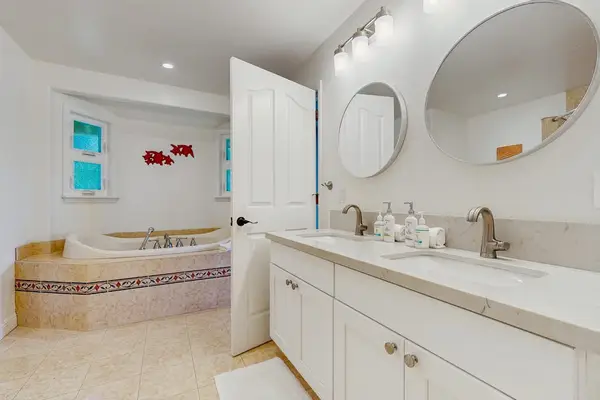 Luxurious primary en suite bathroom with dual sinks, a relaxing jetted garden tub, and a spacious walk-in shower.