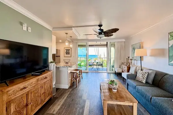 Spacious lounge features wood flooring, comfortable sofas, and tropical artwork