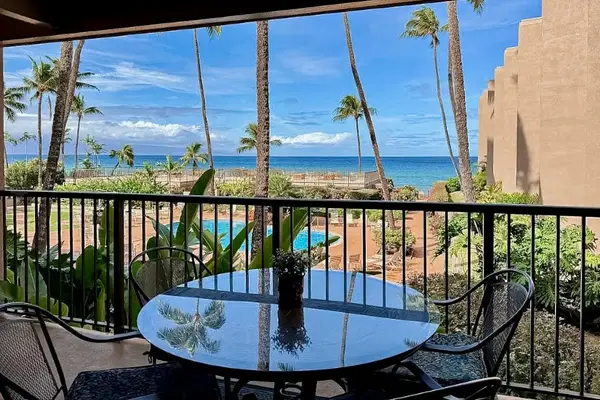 Balcony dining area overlooks tropical gardens, blue water, and scenic coastline