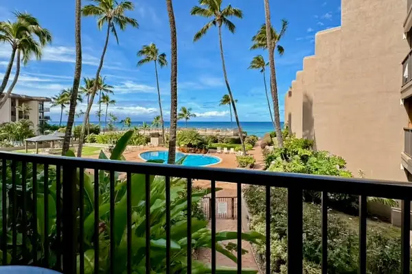 Ocean-facing balcony features comfortable chairs, palm trees, and coastal scenery