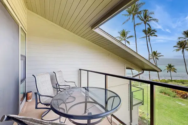 Lanai with Pacific Ocean views and tropical trees blowing in the breeze.