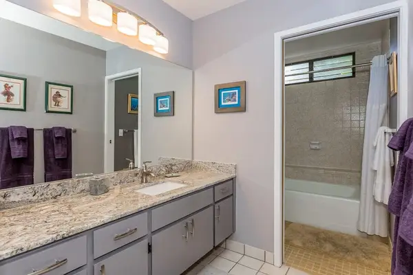 Full bathroom features granite counters dual sinks and glass shower
