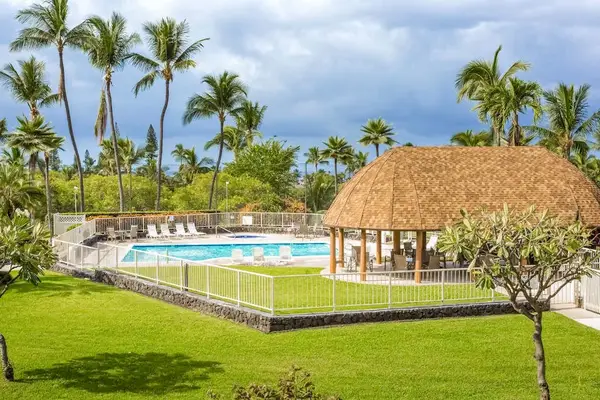 Pool and court sit beside manicured lawns and swaying palms