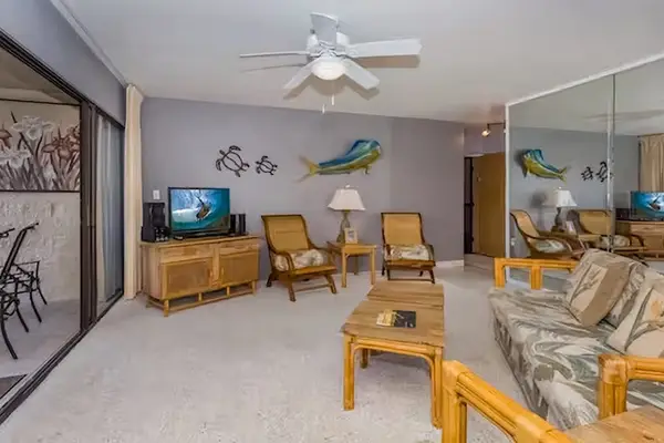 Comfortable living room features coastal artwork seating and ceiling fan