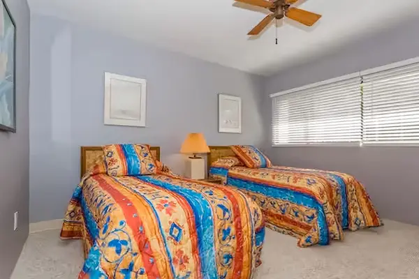 Second bedroom offers twin beds colorful accents and fan comfort