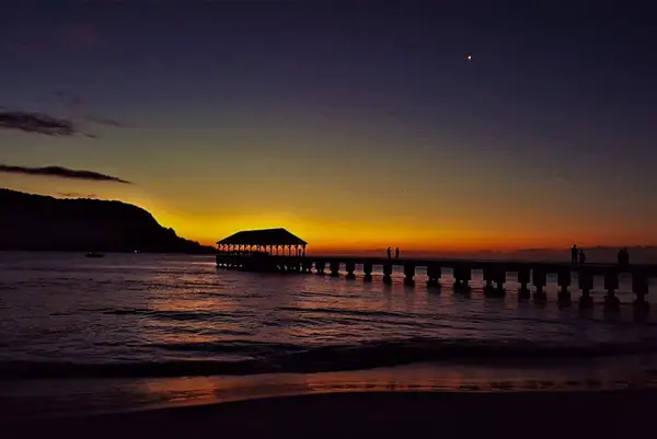 Twilight settles over waters as pier lights guide evening reflections