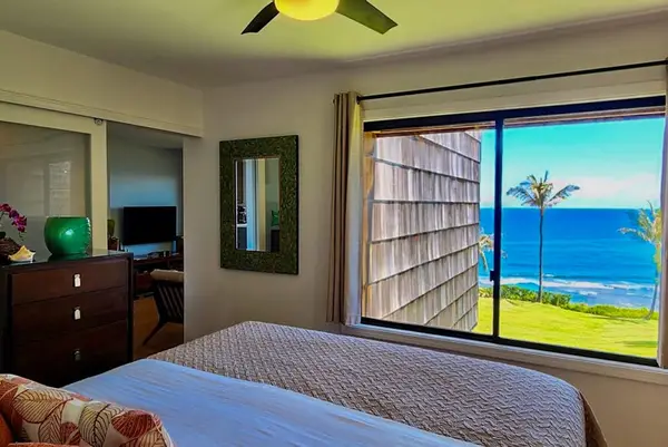 First Bedroom offers ocean views beside neatly made inviting bed