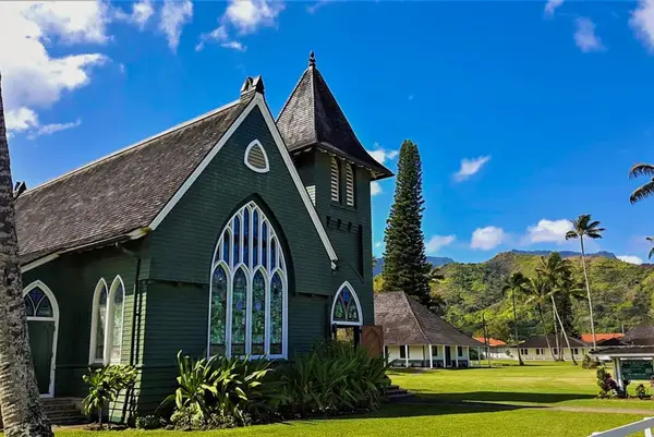 Historic island church stands beside manicured lawns under clear skies
