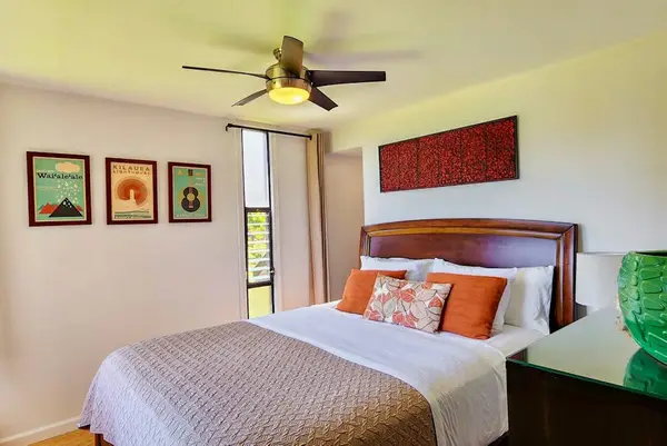 Bedroom features comfortable bed colorful artwork and ceiling fan