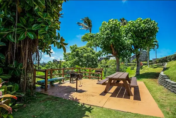 Shaded patio picnic table sits among tropical trees and lawns