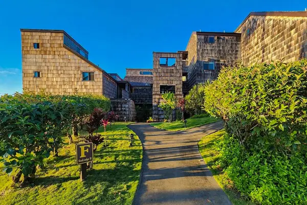 Stone resort buildings line sunny garden pathway toward island views
