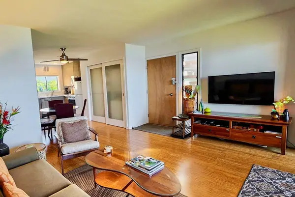 Open living room pairs seating with television and island views