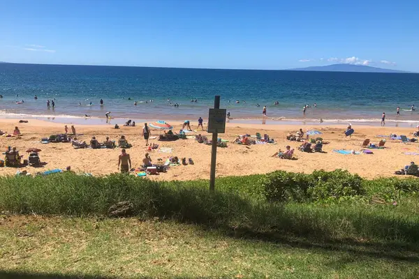 Sunny beach with clear blue water and mountain views