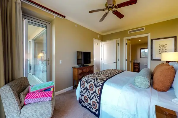Relaxing bedroom setup featuring a flat-screen TV on a wooden console, a plush accent chair, and seamless access to outdoor seating.