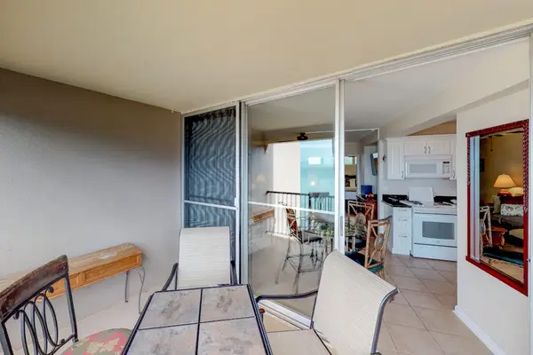 Featuring a glass-topped dining table and metal-framed chairs overlooking the ocean.
