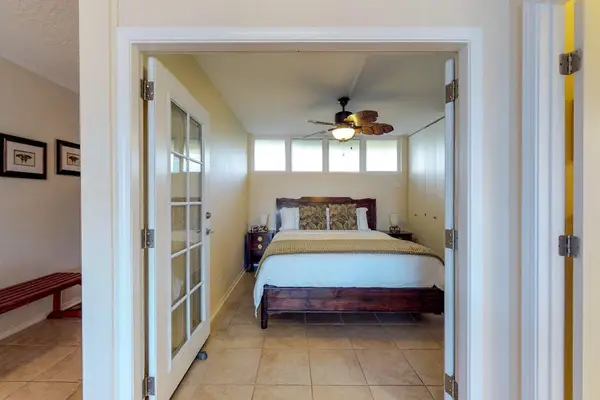 Bedroom, featuring a king bed, French doors, and a palm leaf fan.