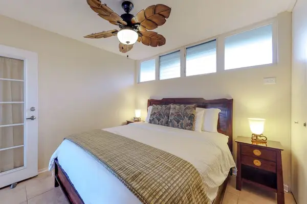 Bedroom, featuring a king bed, French doors, and a palm leaf fan.
