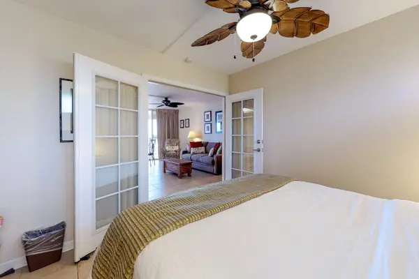 Bedroom, featuring a king bed, French doors, and a palm leaf fan.