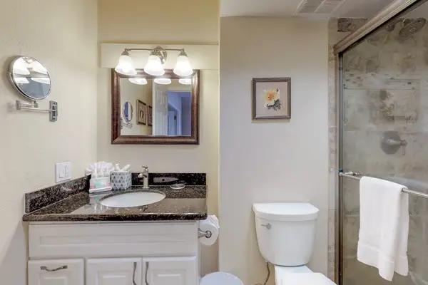 This bathroom features a dark granite countertop with an undermount sink and a light-colored vanity.