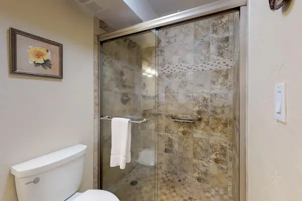 This bathroom features a walk-in shower with stone-look tile walls.