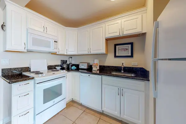The kitchen features clean white cabinetry paired with dark countertops.