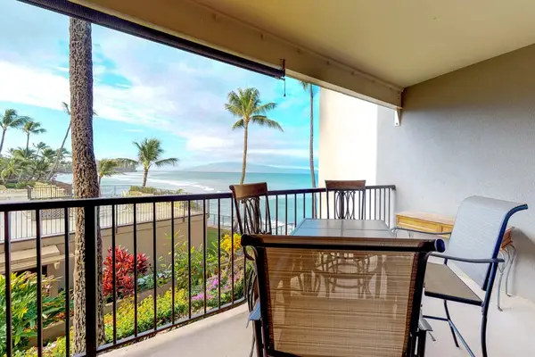 Featuring a glass-topped dining table and metal-framed chairs overlooking the ocean.