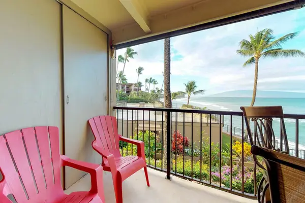 Featuring a glass-topped dining table and metal-framed chairs overlooking the ocean.