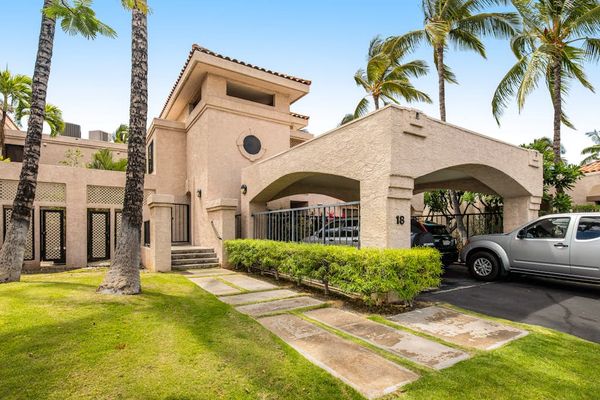 Resort entrance showcases architecture, palms, pathways, landscaping, and parking area