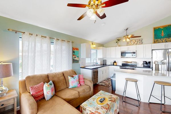 Bright open-concept living room and kitchen layout featuring a cozy sectional sofa, breakfast bar seating, and full appliances! 🛋️✨