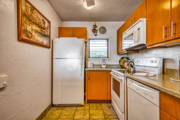 Spacious kitchen layout featuring a refrigerator, stove, microwave, double sink, and ample cabinet storage