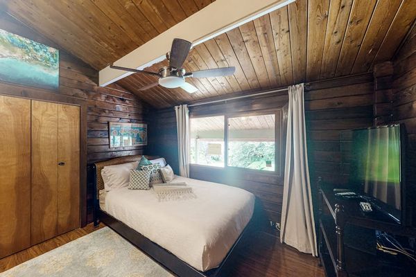 King bedroom with ceiling fan and flat screen tv.