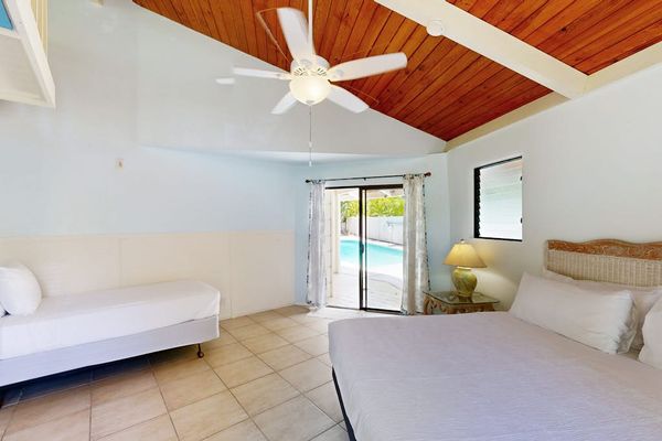 Bedroom sleeping area features ceiling fan windows and tile flooring