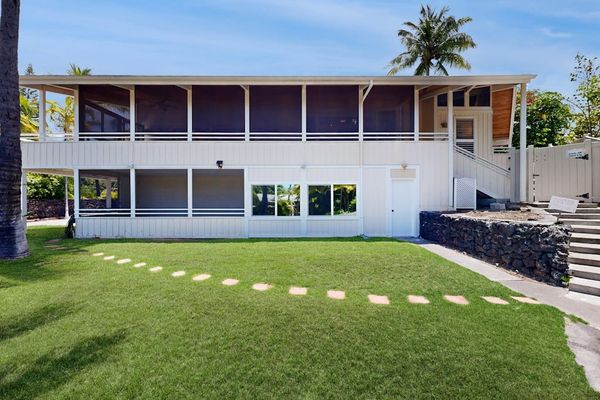 Landscaped lawn frames the home with palms and stepping stones