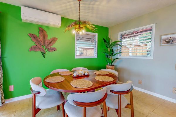 Green dining area offers cheerful seating beneath playful tropical artwork