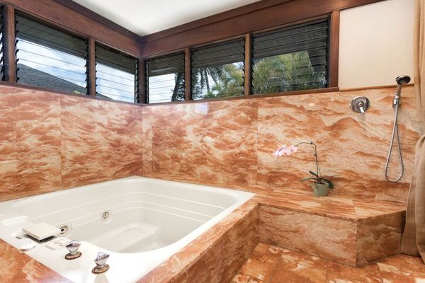 Marble bathroom features a deep bathtub, tiled walls, and windows