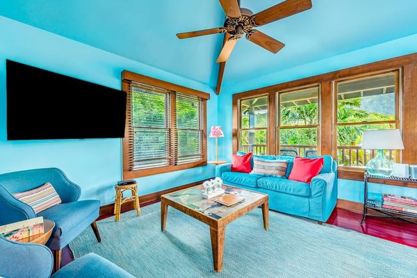 Sunlit living room features blue walls, comfortable sofas, and windows
