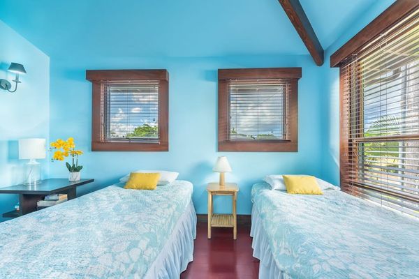 Modern bedroom features twin beds, fresh linens, and garden views