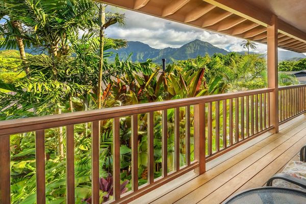 Covered balcony overlooks lush tropical foliage and dramatic mountain scenery