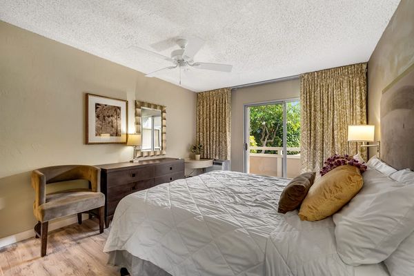 Alternate Angle of Primary Bedroom Highlighting Wooden Dresser, Accent Chair, and Balcony View