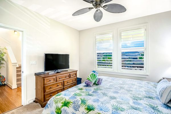 Guest bedroom with king bed, ceiling fan and a flat screen tv.