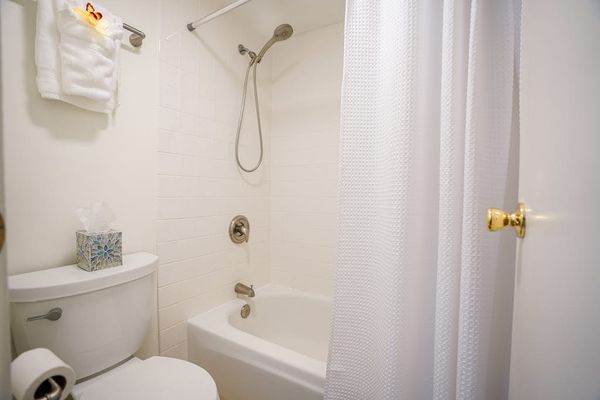 Clean, full bathroom featuring a tub-shower combo and fresh amenities