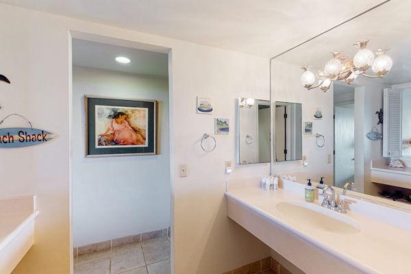 Bathroom vanity features mirror lighting polished fixtures and spacious counters