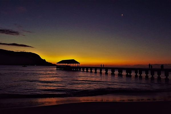 Twilight settles over waters as pier lights guide evening reflections