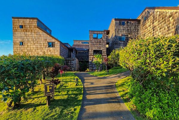 Stone resort buildings line sunny garden pathway toward island views