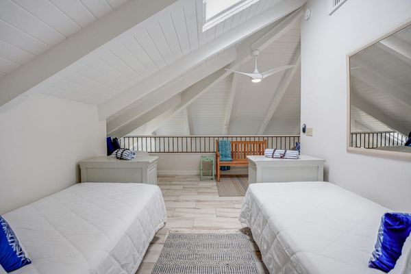 Cozy loft bedroom with two twin beds and vaulted ceilings.
