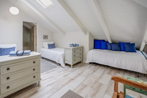 Bright loft bedroom featuring twin beds and vaulted ceilings.