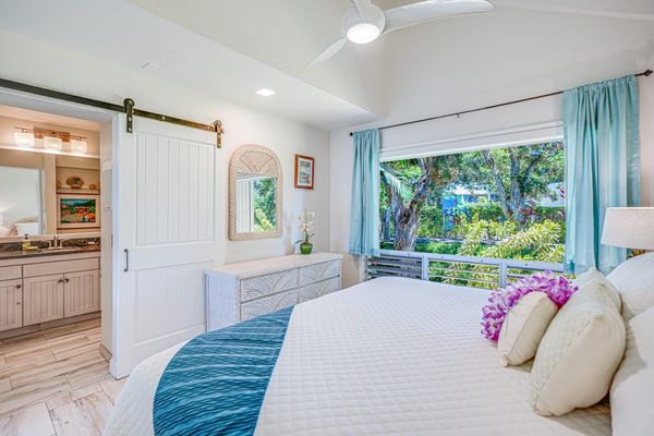 Bright primary bedroom with tropical décor and natural light.
