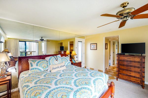 Cozy studio showcases patterned bedding, dresser, ceiling fan, and artwork