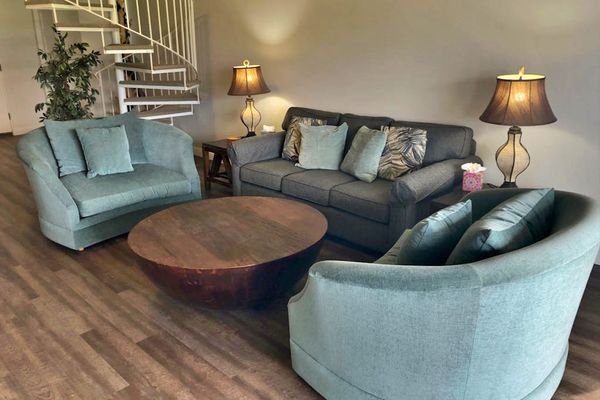 Comfortable living room offers sofas, lamps, and warm wood flooring